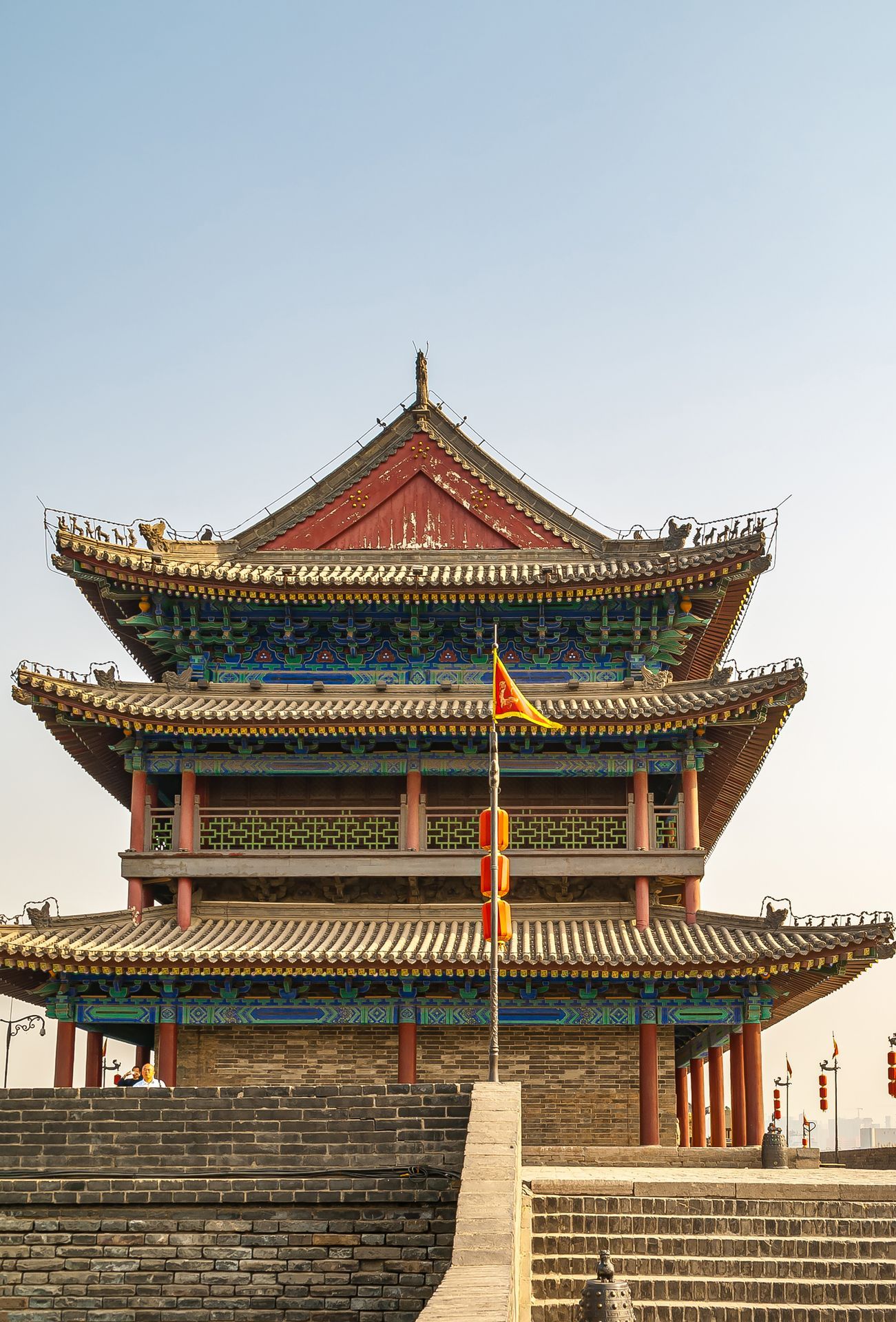 Xian, China - May 1, 2010: Huancheng City Wall brown stone ramparts. Corner tower is highly decorated in blues and reds. Light blue sky. Stairway up and flag.