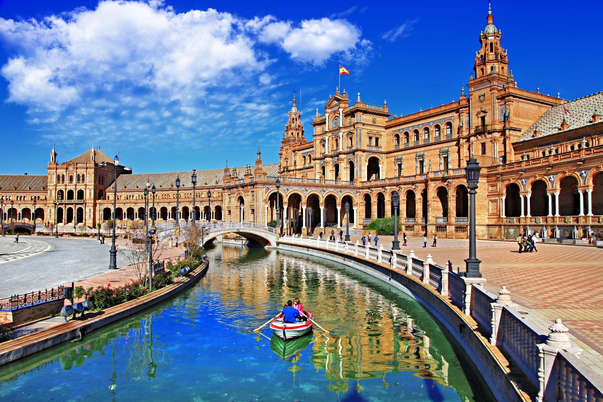 Panoramic View of Plaza de Espana in Seville with Romantic Couple Rowing Boat. Iconic Moorish Revival Architecture and Canal in Maria Luisa Park. Andalusia Spain. World Print Quality.