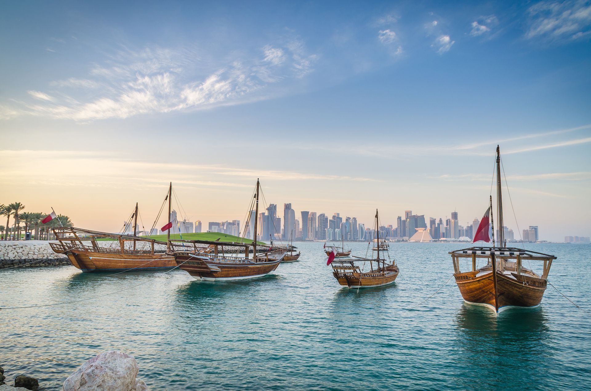 Dhows moored off Museum Park in central Doha, Qatar, Arabia, with some of the buildings from the city's commercial port in the background.