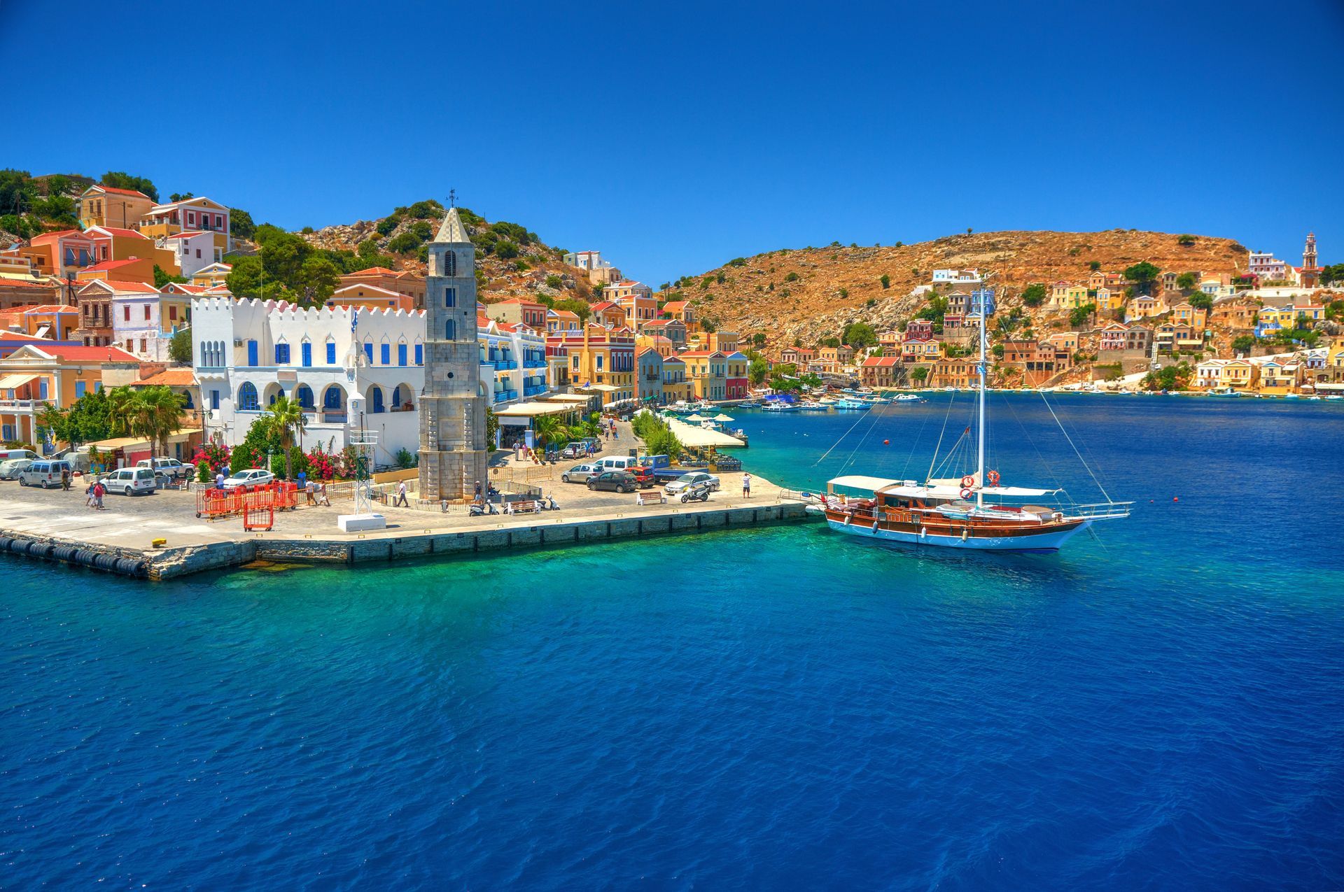 View on Greek sea Simy island harbor port, classical ship yachts, houses on island hills, tourists Aegean Sea bay. Greece islands holidays vacation travel tours from Rhodos island. Greece architecture