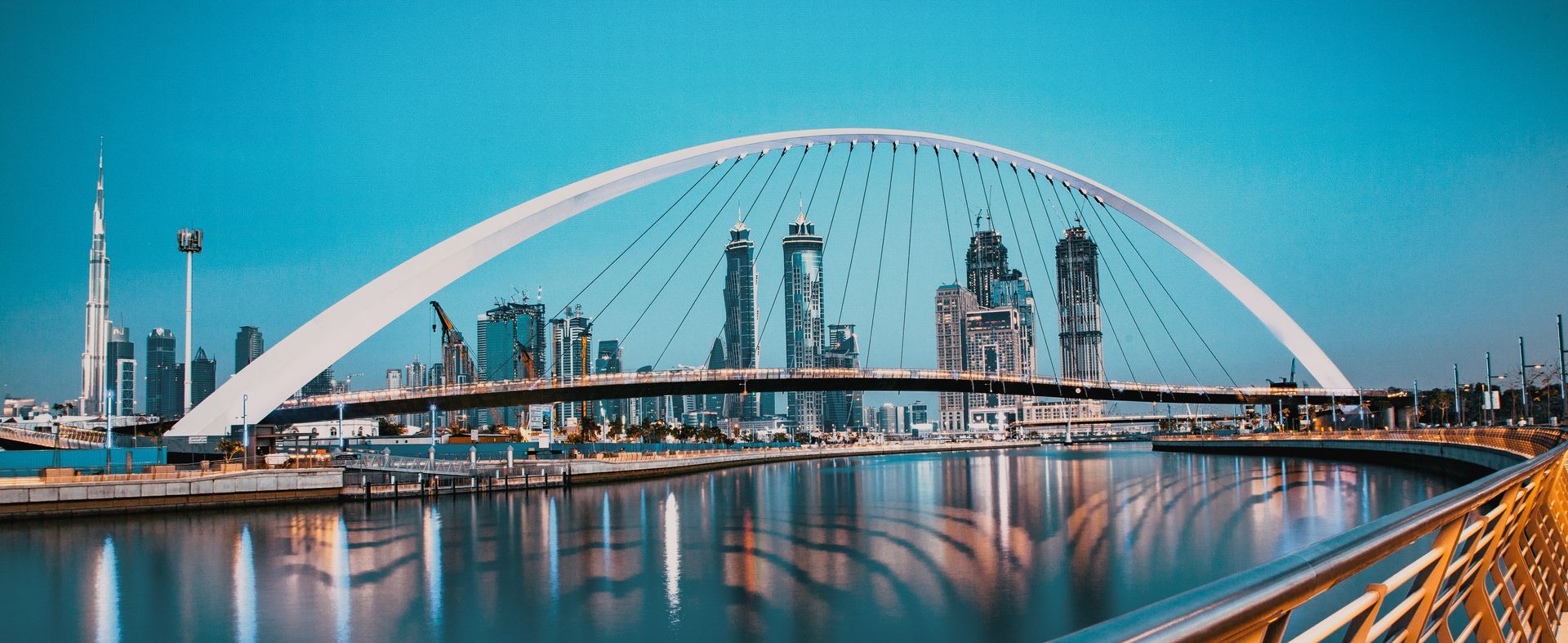 colorful sunset over Dubai Downtown skyscrapers and the newly built Tolerance bridge as viewed from the Dubai water canal