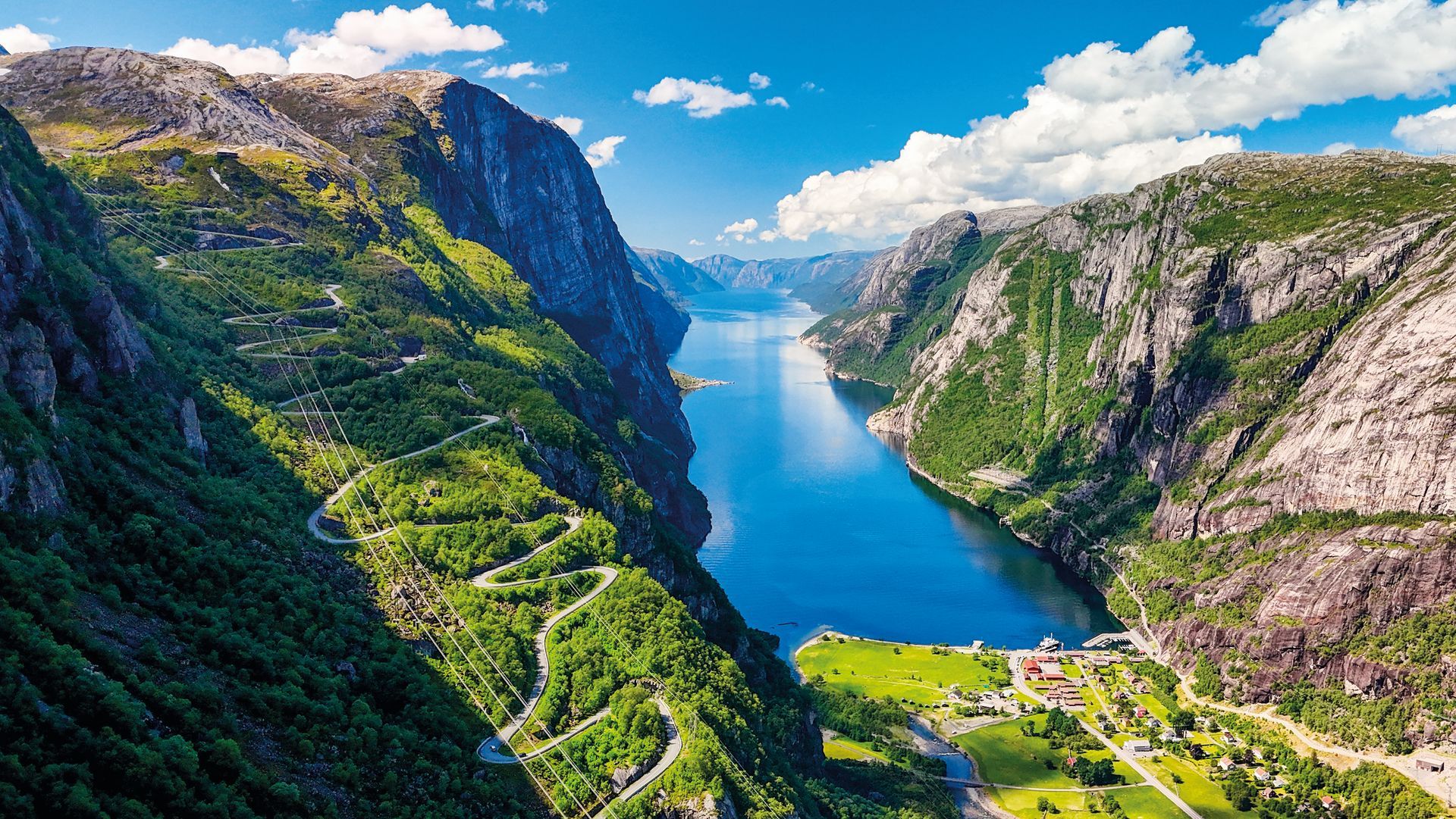 A breathtaking drone aerial view of a Norwegian fjord, showcasing towering cliffs, lush greenery, and the crystal-clear waters of the fjord. Kjerag, Lysebotn, Lysefjorden, Norway