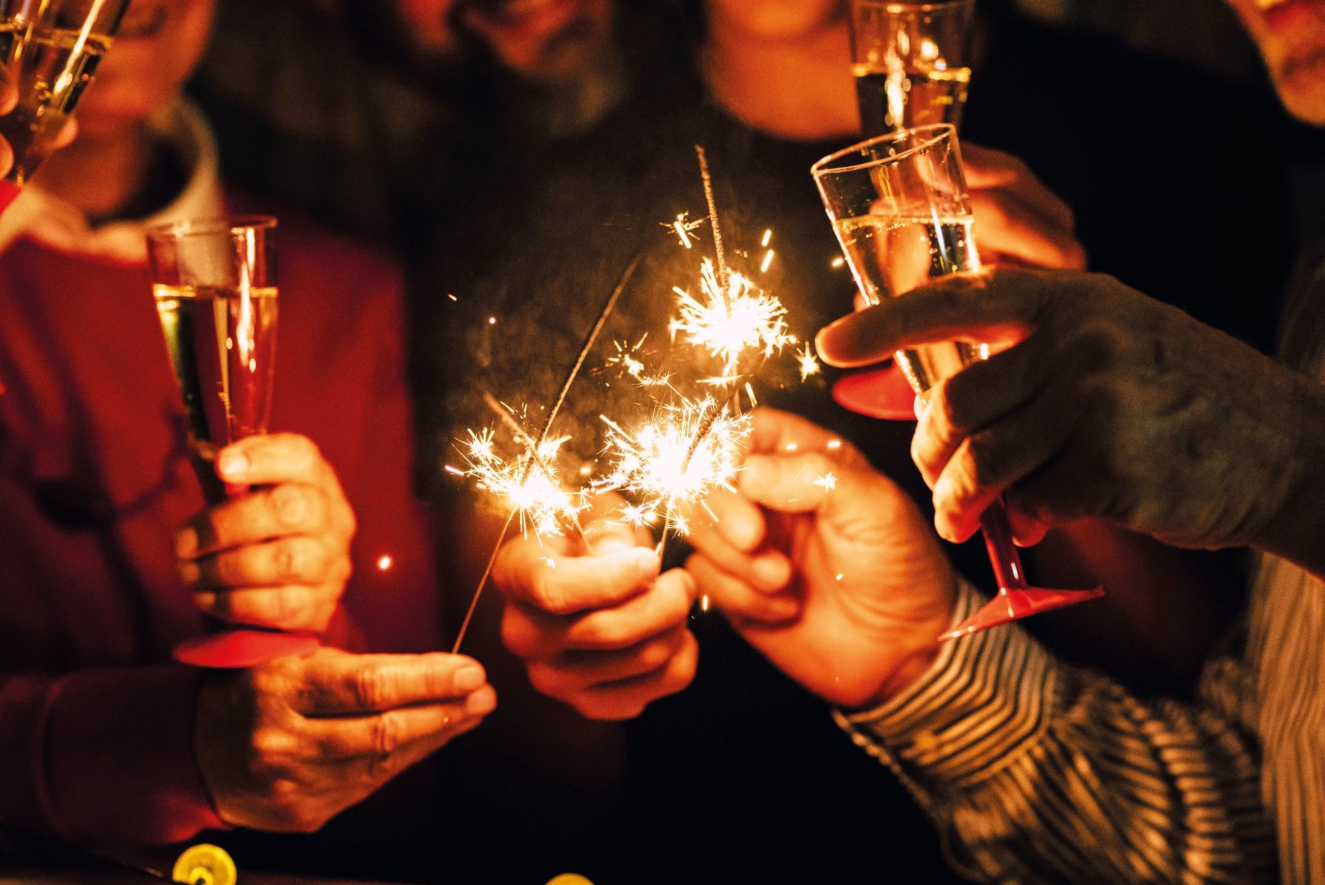 close up of people celebrate new year eve with sparklers and sparkling wine - nightlife concept - birthday or party friends having fun together